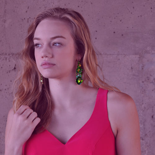 a young woman in a brightly colored dress posing with unique earrings